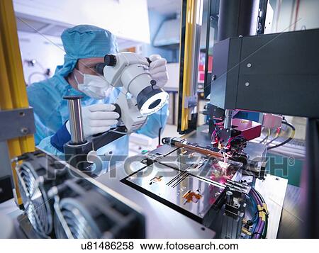 Stock Photo - Electronics worker checking component in clean room. Fotosearch