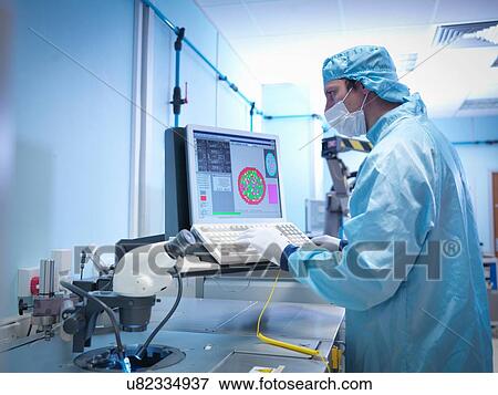 Stock Photo - Electronics worker checking silicon wafer in clean room laboratory. Fotosearch