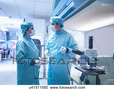 Stock Image - Electronics worker in clean room with silicon wafer. Fotosearch