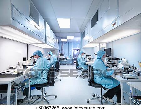 Stock Photograph - Electronics workers in clean room assembling electronic components. Fotosearch
