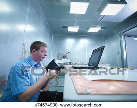 Engineer carrying out electro static discharge (ESD) testing using air discharge probe on copper table in screened room View Large Photo Image Stock Photo - Engineer carrying out electro static discharge (ESD) testing using air discharge probe on copper table in screened room. Fotosearch