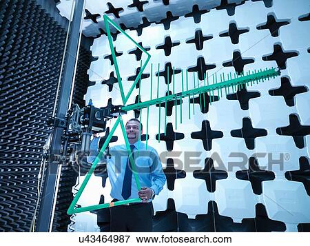 Stock Photo - Engineer checking a bilog antenna's height for electromagnetic compatibility (EMC) radiated immunity testing in a semi anechoic chamber. Fotosearch