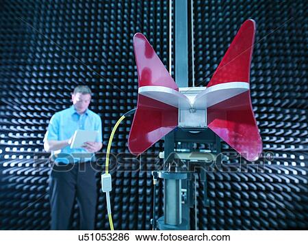 Stock Photograph - Engineer in anechoic chamber with horn antenna set up for electromagnetic compatibility (EMC) radiated emission testing. Fotosearch