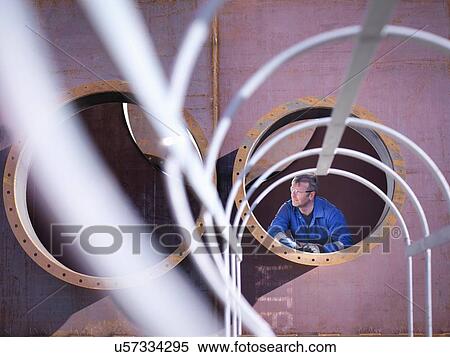 Stock Photography - Engineer inspecting large steel superstructure in engineering factory. Fotosearch