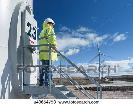 Stock Image - Engineer standing on stairway at windfarm. Fotosearch