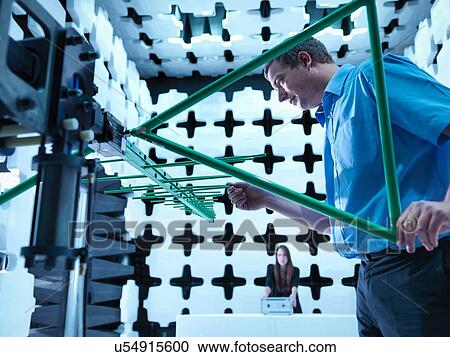 Stock Image - Engineers checking a bilog antenna for electromagnetic compatibility (EMC) radiated immunity testing in a semi anechoic chamber relative to the electronic equipment under test (EUT). Fotosearch