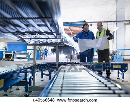 Engineers inspecting new conveyor in engineering factory View Large Photo Image Stock Photo - Engineers inspecting new conveyor in engineering factory. Fotosearch