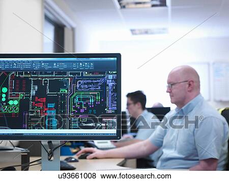 Stock Photo - Engineers looking at CAD designs in office of engineering factory. Fotosearch