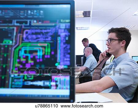 Stock Image - Engineers on phone and looking at CAD designs in engineering factory office. Fotosearch