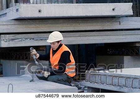Stock Photo - Factory worker attaching hook to concrete block in concrete reinforcement factory. Fotosearch