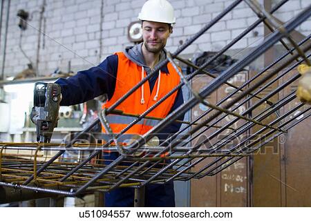 Factory worker attaching steel mesh at concrete reinforcement factory View Large Photo Image Stock Photo - Factory worker attaching steel mesh at concrete reinforcement factory. Fotosearch