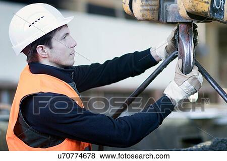 Stock Photo - Factory worker attaching winch in concrete reinforcement factory. Fotosearch