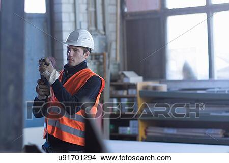 Picture - Factory worker checking component in concrete reinforcement factory. Fotosearch