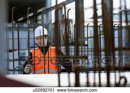 Stock Image - Factory worker choosing wire mesh in concrete reinforcement factory. Fotosearch