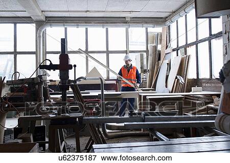 Stock Photo - Factory worker examining steel rod at concrete reinforcement factory. Fotosearch