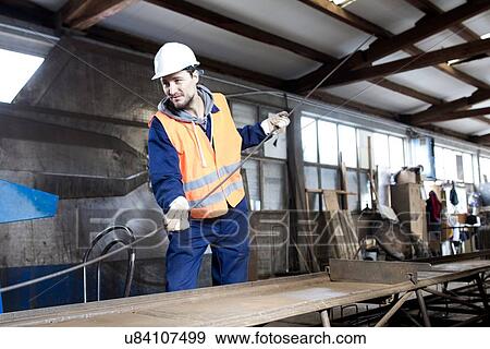 Stock Photo - Factory worker moving steel rod at concrete reinforcement factory. Fotosearch