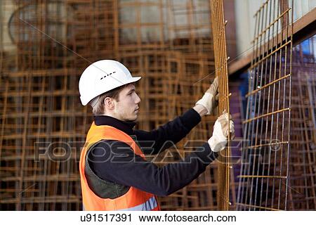 Stock Image - Factory worker moving wire mesh in concrete reinforcement factory. Fotosearch