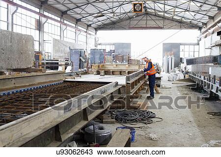 Stock Image - Factory worker on production line in concrete reinforcement factory. Fotosearch