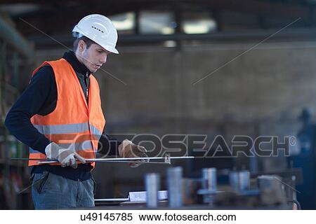 Stock Photography - Factory worker selecting metal rod in concrete reinforcement factory. Fotosearch