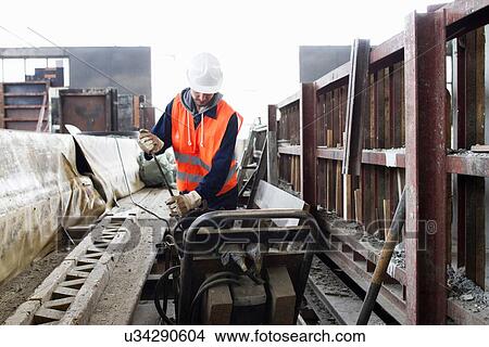 Picture - Factory worker selecting steel rod at concrete reinforcement factory. Fotosearch