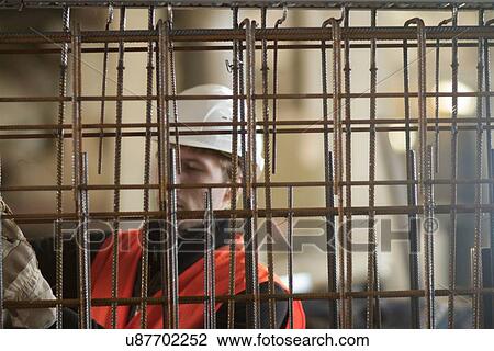 Stock Image - Factory worker selecting wire mesh in concrete reinforcement factory. Fotosearch