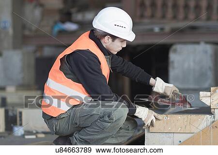 Stock Photo - Factory worker using finishing trowel on concrete in concrete reinforcement factory. Fotosearch