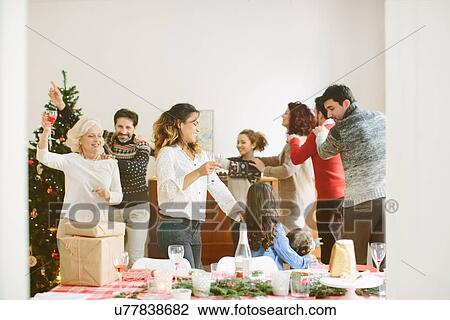 Stock Image - Family doing the conga at family Christmas party. Fotosearch