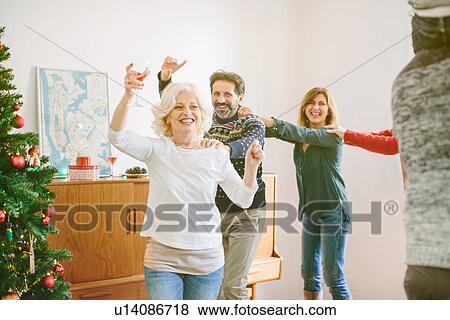 Stock Photo - Family doing the conga at family Christmas party. Fotosearch