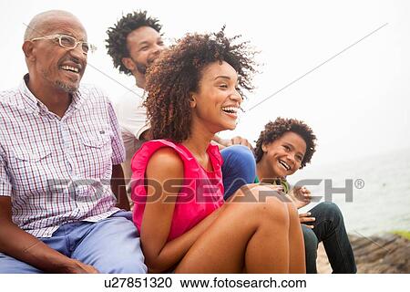 Stock Image - "Family of four sitting on Ipanema beach, Rio De Janeiro, Brazil". Fotosearch