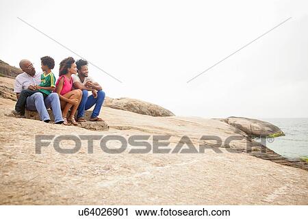"Family of four sitting on rock, Ipanema beach, Rio De Janeiro, Brazil" View Large Photo Image Stock Image - "Family of four sitting on rock, Ipanema beach, Rio De Janeiro, Brazil". Fotosearch
