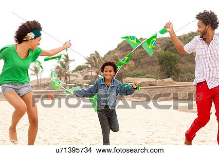 Picture - "Family playing with string of flags on beach, Rio de Janeiro, Brazil". Fotosearch