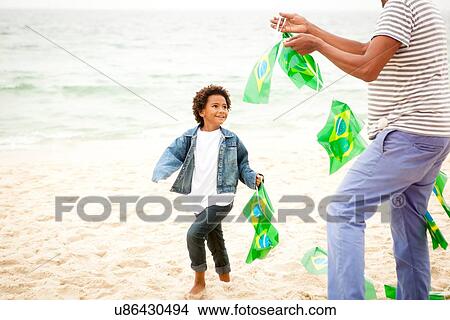 "Family playing with string of flags on beach, Rio de Janeiro, Brazil" View Large Photo Image Picture - "Family playing with string of flags on beach, Rio de Janeiro, Brazil". Fotosearch
