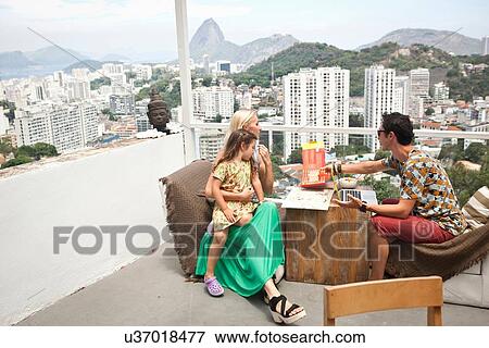 "Family sitting at table on balcony, father using laptop" View Large Photo Image Stock Photo - "Family sitting at table on balcony, father using laptop". Fotosearch