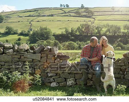 Farming couple and dog sitting on dry stone wall in field View Large Photo Image Stock Image - Farming couple and dog sitting on dry stone wall in field. Fotosearch