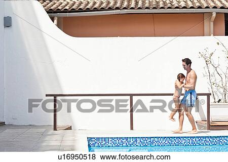 Stock Photo - "Father and daughter by side of outdoor pool, father lifting daughter". Fotosearch