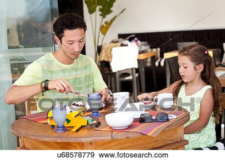Stock Photo - Father and daughter sitting at breakfast table together. Fotosearch