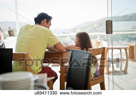 Stock Image - Father and daughter sitting at table together. Fotosearch