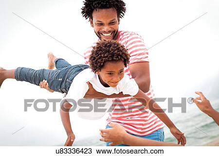 Stock Image - Father and son playing on beach. Fotosearch