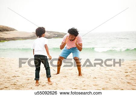 Stock Photograph - Father and son playing on beach. Fotosearch