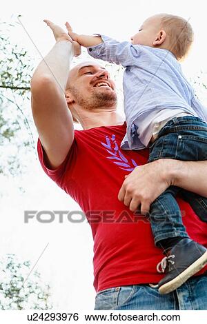 "Father holding son, son giving father a high five, low angle view" View Large Photo Image Stock Photograph - "Father holding son, son giving father a high five, low angle view". Fotosearch