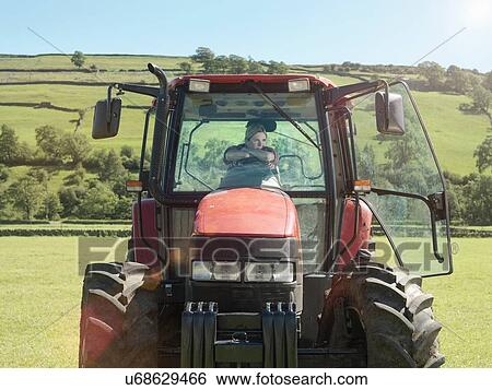 Stock Photograph - Female farmer driving tractor in field. Fotosearch