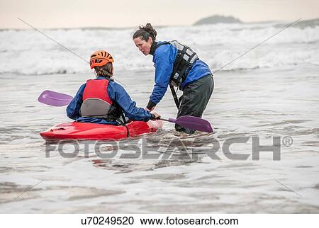 Female instructor helping woman in sea kayak View Large Photo Image Stock Image - Female instructor helping woman in sea kayak. Fotosearch