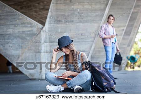 "Female student sitting on floor with book, man watching" View Large Photo Image Stock Photo - "Female student sitting on floor with book, man watching". Fotosearch