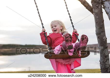 Stock Image - "Female toddler swinging on playground swing, Reykjavik, Iceland". Fotosearch