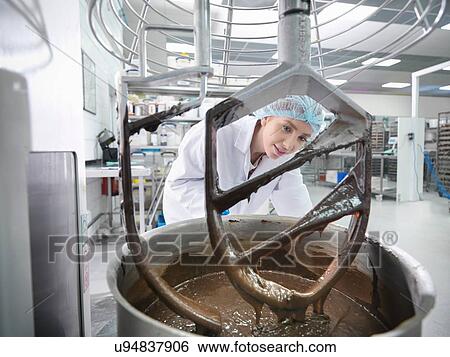 Stock Photograph - Female worker mixes chocolate in cake factory. Fotosearch