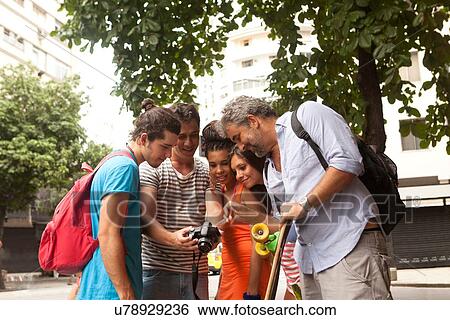 Stock Photograph - "Five tourist friends reviewing photos on digital camera, Copacabana town, Rio De Janeiro, Brazil". Fotosearch