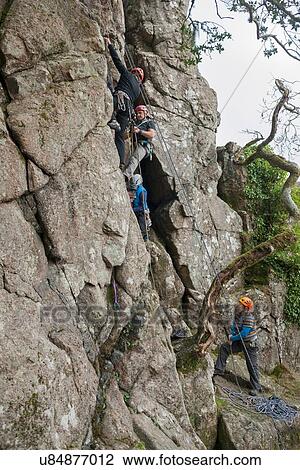 Stock Image - Four people rock climbing. Fotosearch