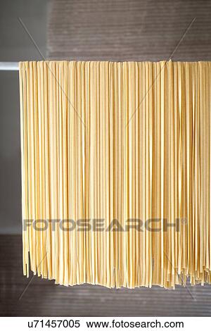 Stock Photography - Fresh tagliatelle drying on rack in factory. Fotosearch