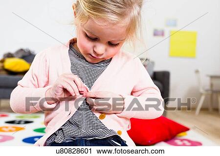 Girl buttoning cardigan View Large Photo Image Stock Image - Girl buttoning cardigan. Fotosearch
