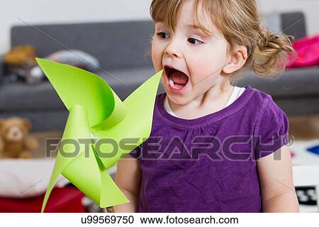 Girl excited over paper windmill at home View Large Photo Image Stock Image - Girl excited over paper windmill at home. Fotosearch